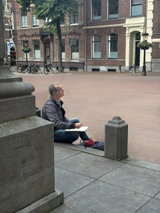 911185 Afbeelding van kunstenaar Jeroen Hermkens op het Domplein Utrecht, terwijl hij een tekening maakt van de ...